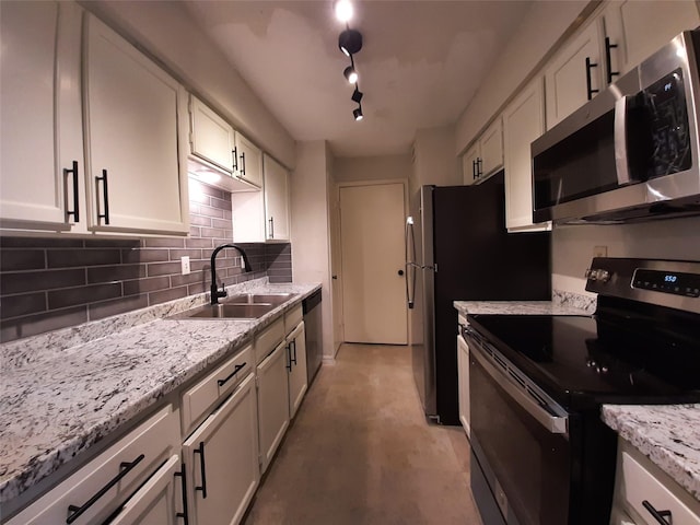 kitchen with white cabinetry, rail lighting, appliances with stainless steel finishes, light stone counters, and sink