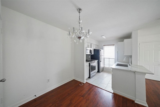 kitchen featuring decorative light fixtures, white cabinetry, stainless steel appliances, sink, and kitchen peninsula