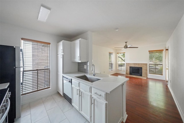 kitchen with backsplash, dishwasher, sink, white cabinetry, and stainless steel fridge