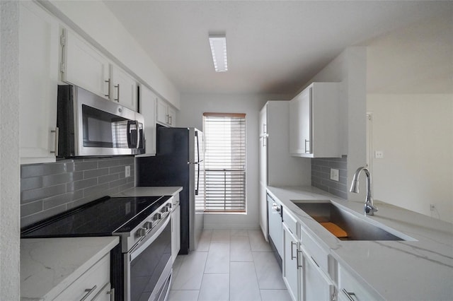 kitchen featuring white cabinets, appliances with stainless steel finishes, sink, backsplash, and light stone counters