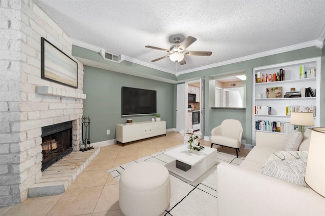 tiled living room with a textured ceiling, ceiling fan, ornamental molding, and a fireplace