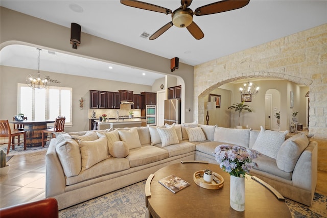 tiled living room with ceiling fan with notable chandelier