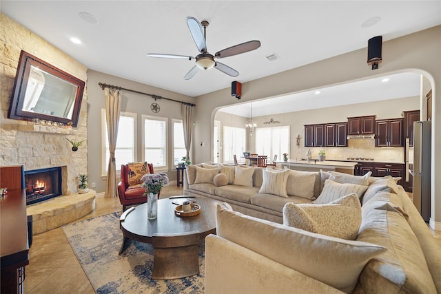 tiled living room featuring ceiling fan and a fireplace