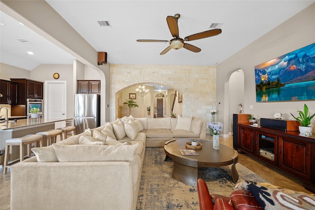 living room featuring vaulted ceiling and ceiling fan with notable chandelier