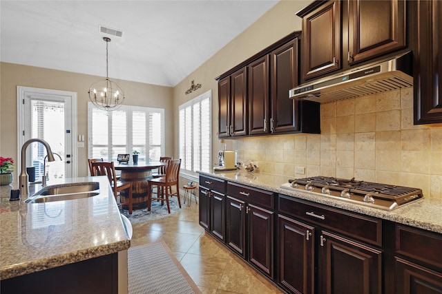 kitchen with light stone countertops, decorative light fixtures, sink, a notable chandelier, and stainless steel gas stovetop