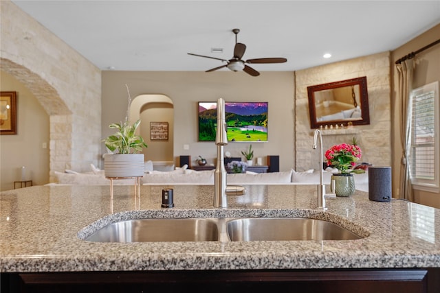 kitchen with light stone counters, sink, and ceiling fan