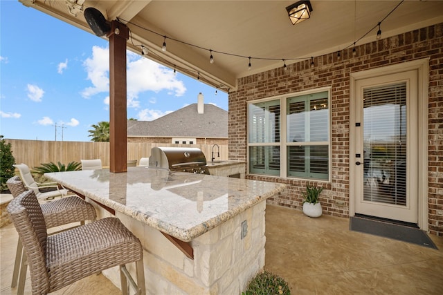 view of patio with area for grilling, exterior kitchen, and an outdoor wet bar