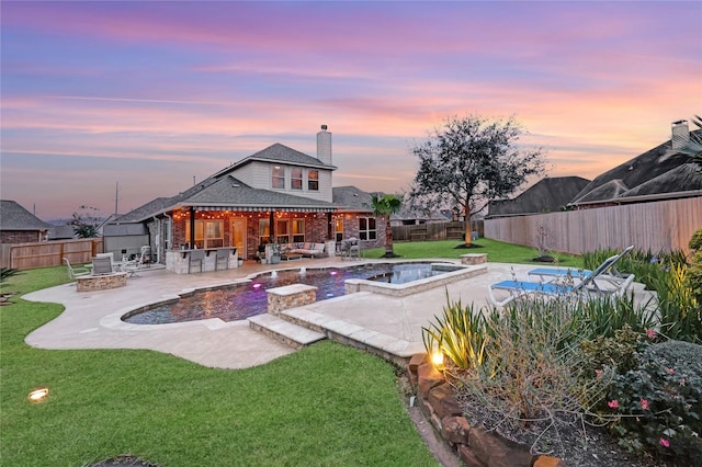 pool at dusk with a bar, a patio area, an outdoor fire pit, a lawn, and area for grilling