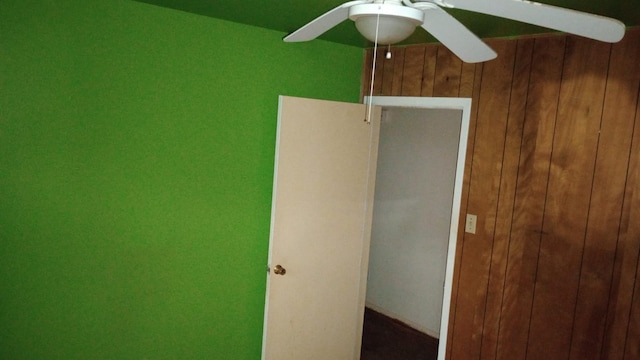 unfurnished room featuring ceiling fan and wooden walls