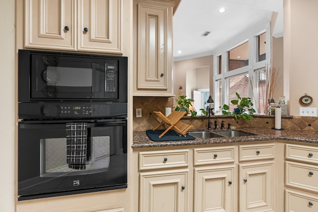 kitchen with dark stone countertops, cream cabinets, and black appliances