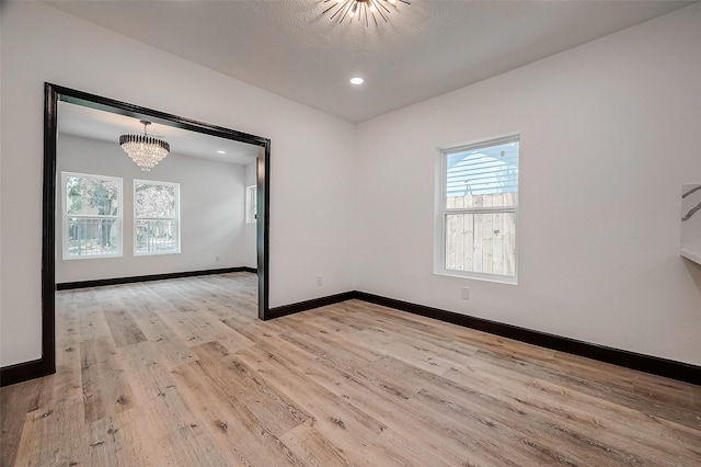 spare room featuring an inviting chandelier and light hardwood / wood-style floors