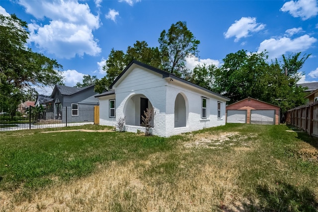 view of front of property featuring a front lawn, a garage, and an outbuilding