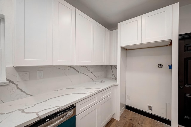 kitchen with backsplash, dishwasher, white cabinetry, light wood-type flooring, and light stone countertops