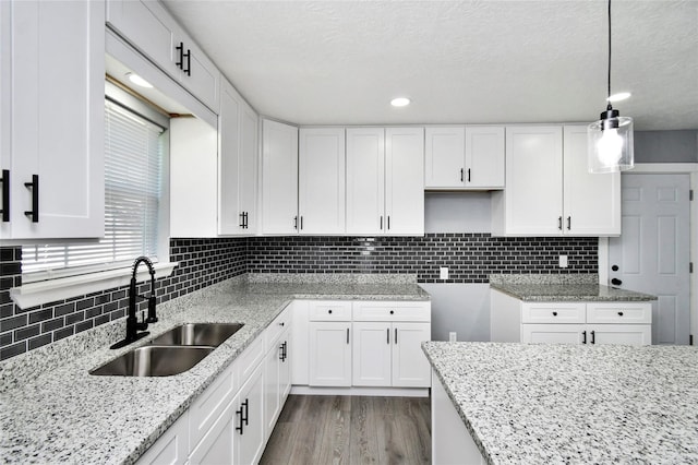 kitchen featuring pendant lighting, sink, white cabinetry, and light hardwood / wood-style flooring