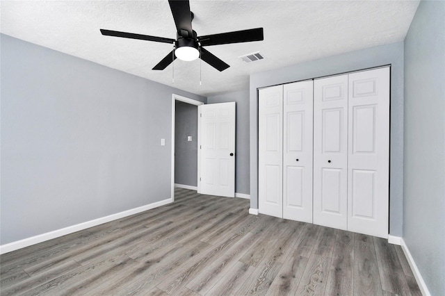 unfurnished bedroom with ceiling fan, wood-type flooring, a closet, and a textured ceiling