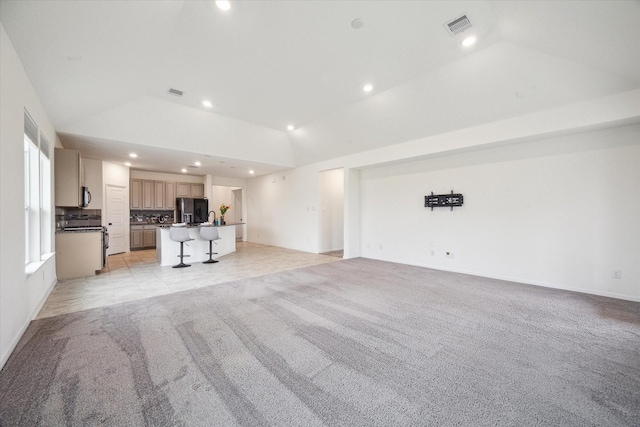 unfurnished living room featuring vaulted ceiling and light colored carpet