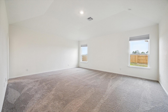 carpeted spare room featuring vaulted ceiling