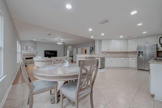 tiled dining room featuring ceiling fan and sink