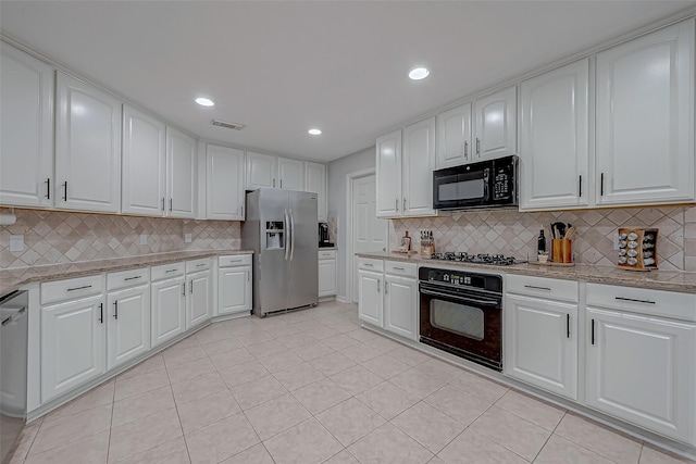 kitchen featuring tasteful backsplash, light stone counters, black appliances, light tile patterned floors, and white cabinets