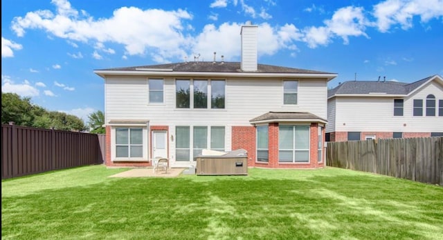 back of property featuring a hot tub, a patio, and a lawn