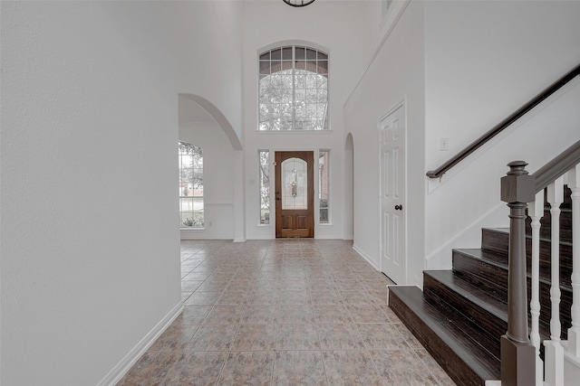 foyer entrance featuring a towering ceiling and light tile patterned floors