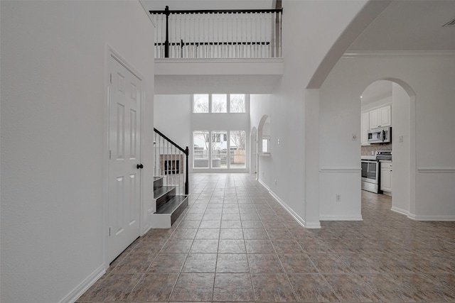 entrance foyer featuring crown molding, a towering ceiling, and light tile patterned flooring