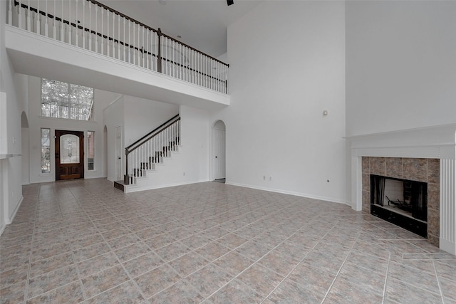 unfurnished living room with a towering ceiling and a tile fireplace