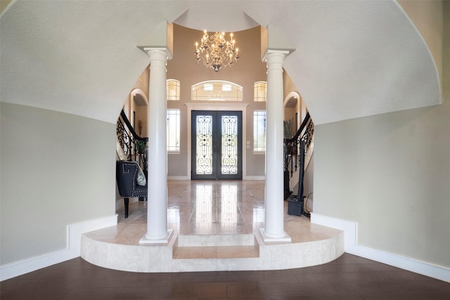 entrance foyer with light hardwood / wood-style floors, ornate columns, and a notable chandelier