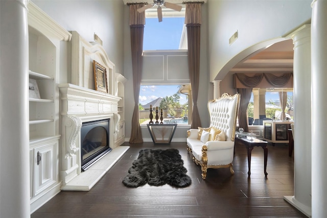 living area featuring decorative columns, hardwood / wood-style floors, a towering ceiling, and ceiling fan