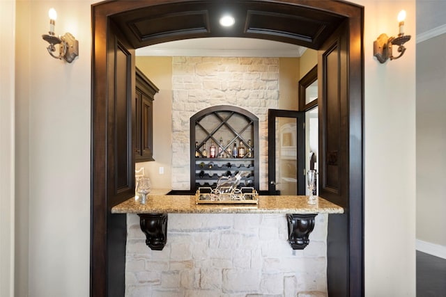 bar featuring ornamental molding and light stone countertops