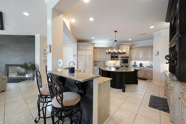 kitchen featuring a kitchen island, light stone countertops, a kitchen breakfast bar, ornamental molding, and light tile patterned floors