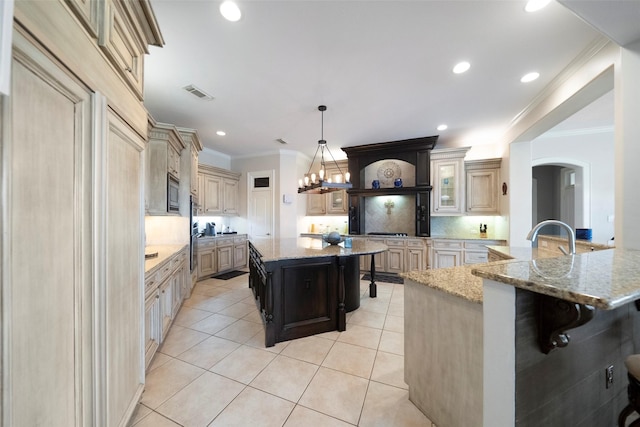 kitchen with light stone counters, backsplash, and a large island