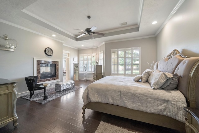 bedroom with ceiling fan, dark wood-type flooring, crown molding, and a raised ceiling