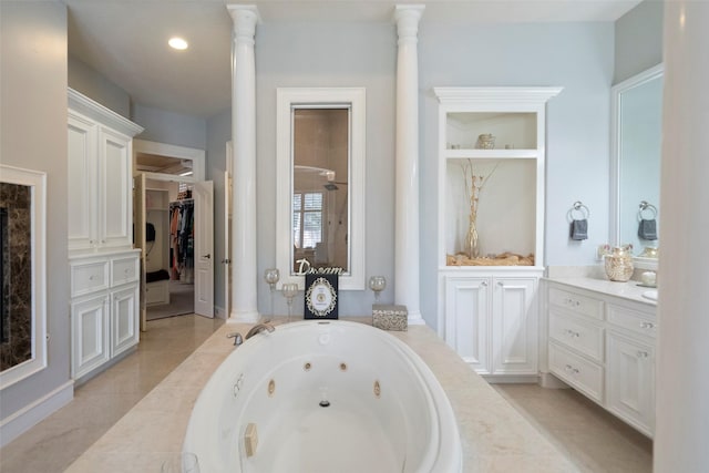 bathroom with a relaxing tiled tub, tile patterned floors, vanity, and ornate columns