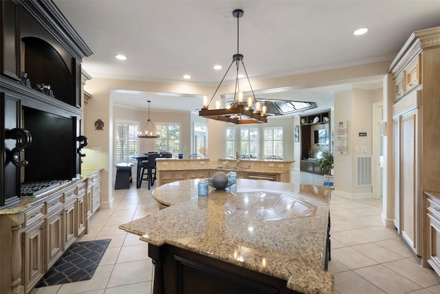 kitchen with light tile patterned floors, ornamental molding, a spacious island, and decorative light fixtures