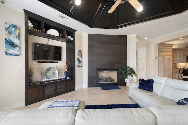 living room with light tile patterned flooring, ceiling fan, ornamental molding, and a tiled fireplace