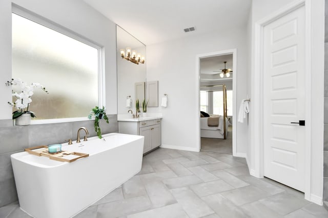 bathroom featuring tile patterned floors, a tub to relax in, vanity, and an inviting chandelier