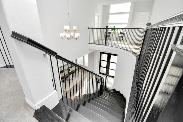 stairway featuring carpet floors, plenty of natural light, and a chandelier