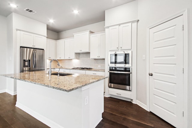 kitchen featuring sink, white cabinets, stainless steel appliances, and an island with sink