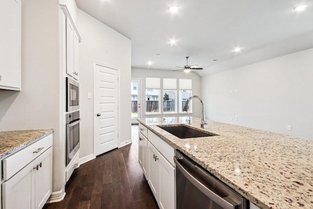 kitchen featuring appliances with stainless steel finishes, white cabinetry, light stone counters, and sink