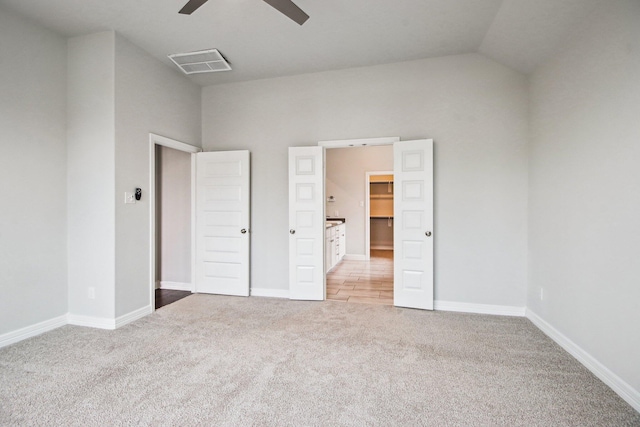 unfurnished bedroom featuring a spacious closet, lofted ceiling, light carpet, and ceiling fan