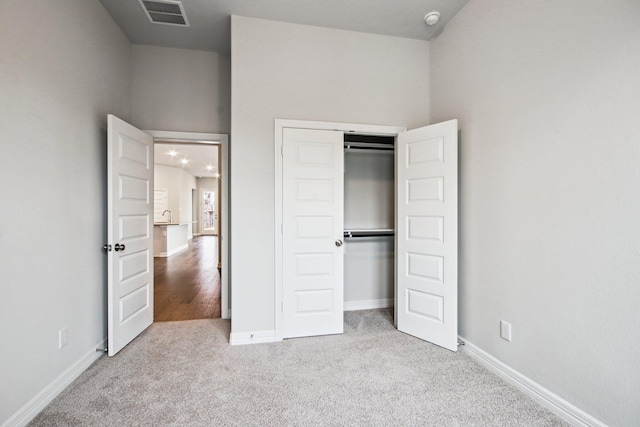 unfurnished bedroom featuring light carpet and a closet