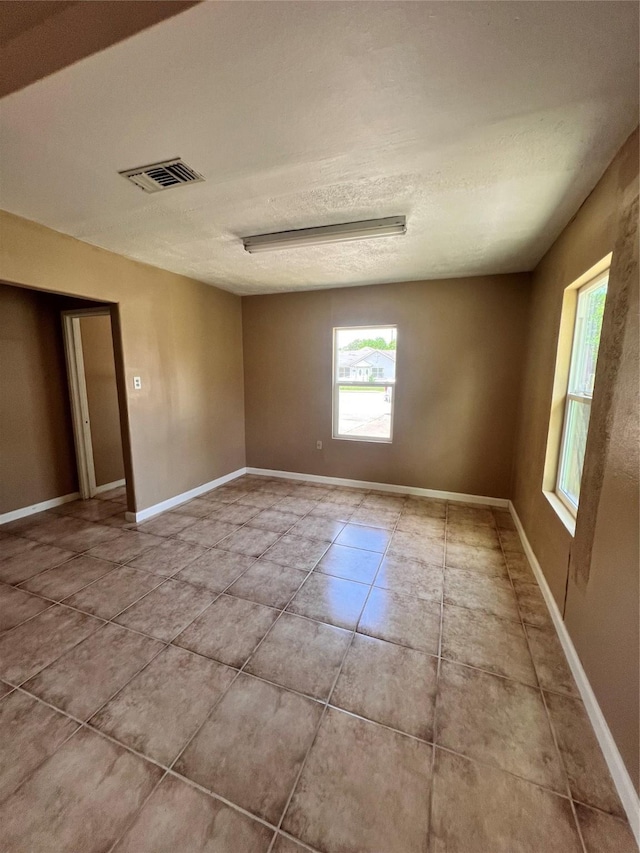 tiled empty room with a textured ceiling