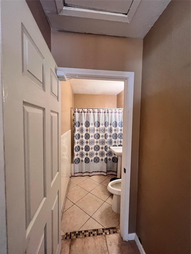 bathroom featuring toilet, tile patterned flooring, and a shower with shower curtain