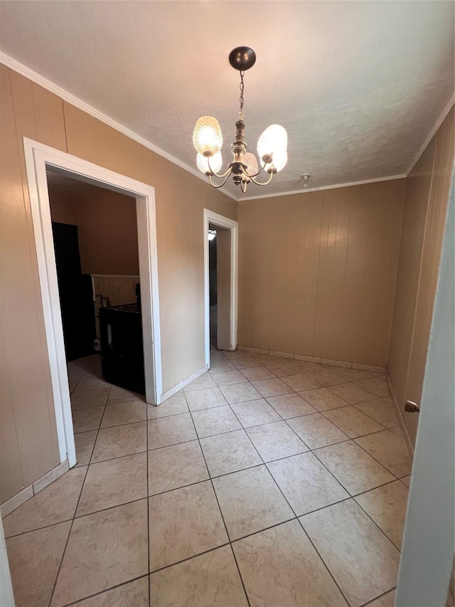 unfurnished dining area featuring an inviting chandelier, light tile patterned floors, wooden walls, a textured ceiling, and ornamental molding