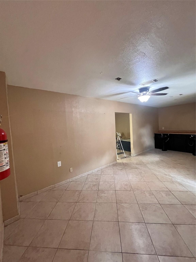 tiled spare room with ceiling fan and a textured ceiling