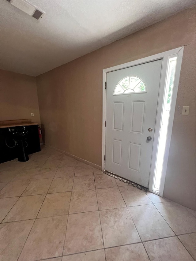 tiled entryway featuring a textured ceiling