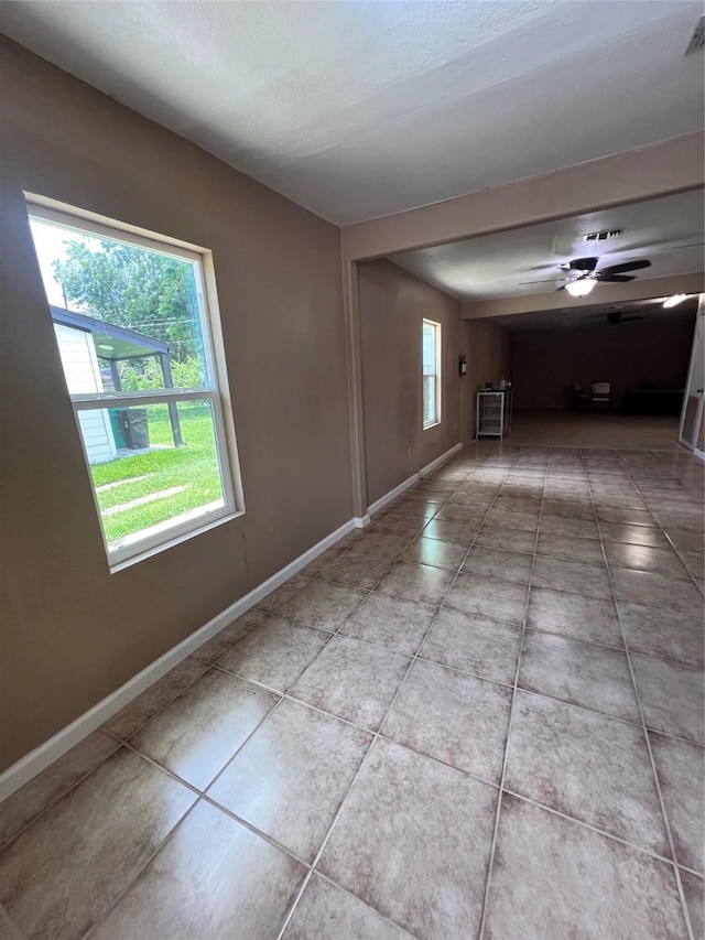 empty room with a textured ceiling, ceiling fan, and tile patterned flooring