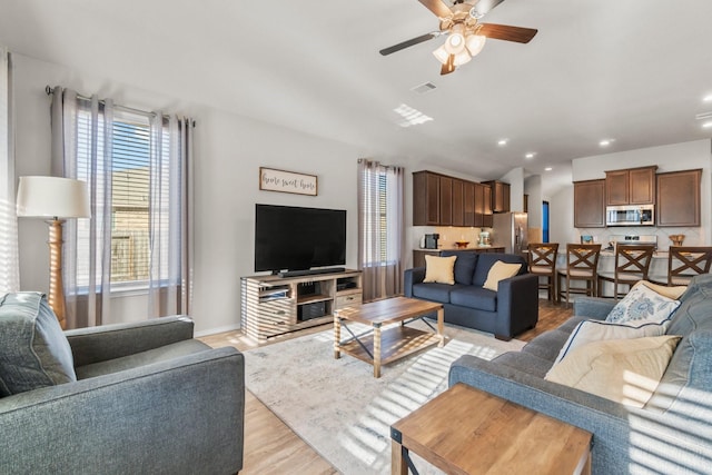 living room with ceiling fan and light wood-type flooring