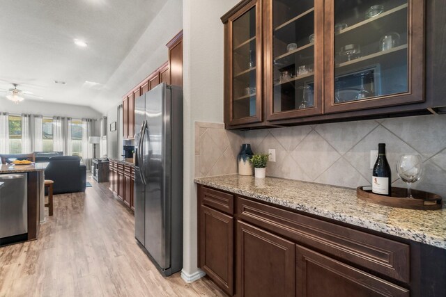 kitchen with ceiling fan, stainless steel appliances, tasteful backsplash, light stone countertops, and light hardwood / wood-style floors